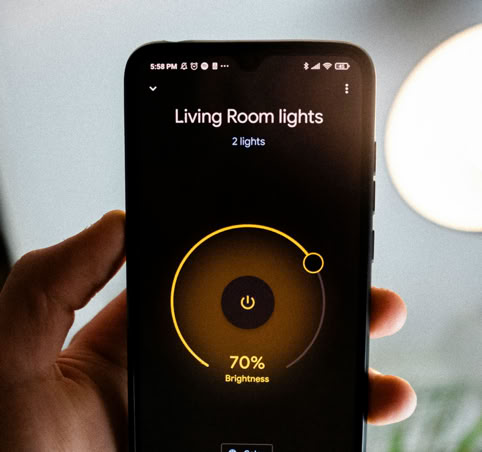 Smartphone mit geöffneter App zur Steuerung der Wohnzimmerbeleuchtung, Helligkeit auf 70 % eingestellt.